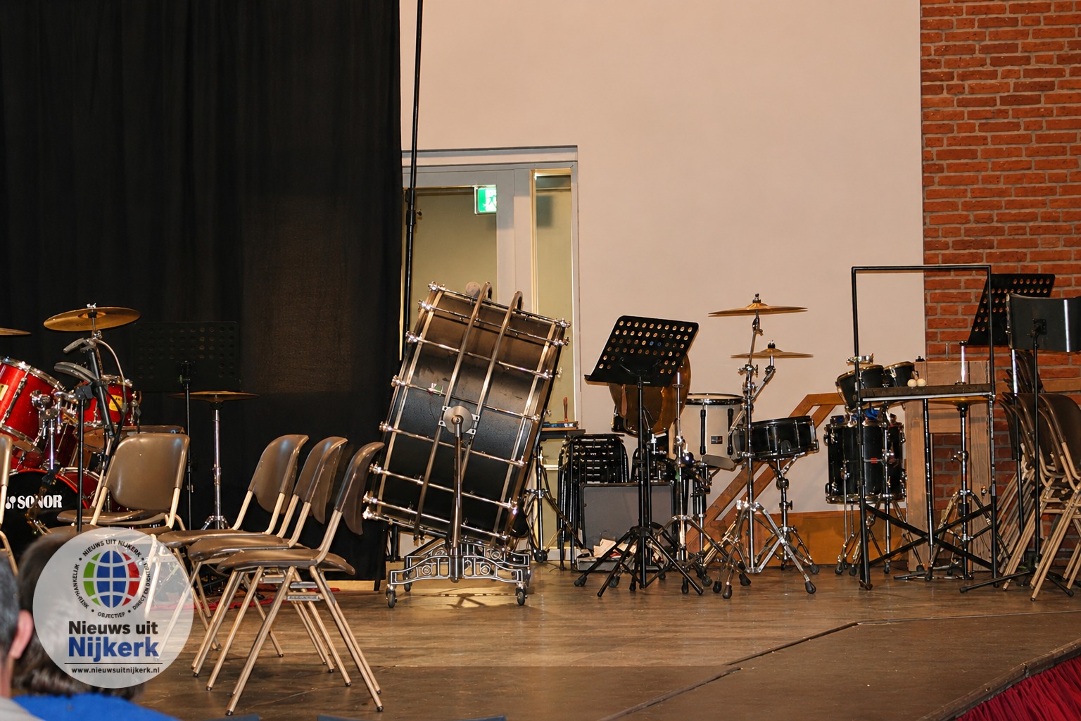 Scherp podium met drums en stoelen.png